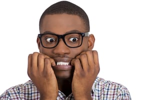 Closeup portrait of young nerdy, unhappy, scared man, student with big glasses biting nails, looking away with a craving for something, anxious, worried, isolated on white background. Face expression-1